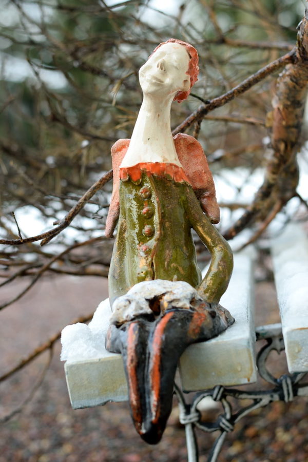 Ceramiczna rzeźba anioła trzymającego psa. Ceramiczny anioł w zielonym kolorze. Siedzący anioł na komodę