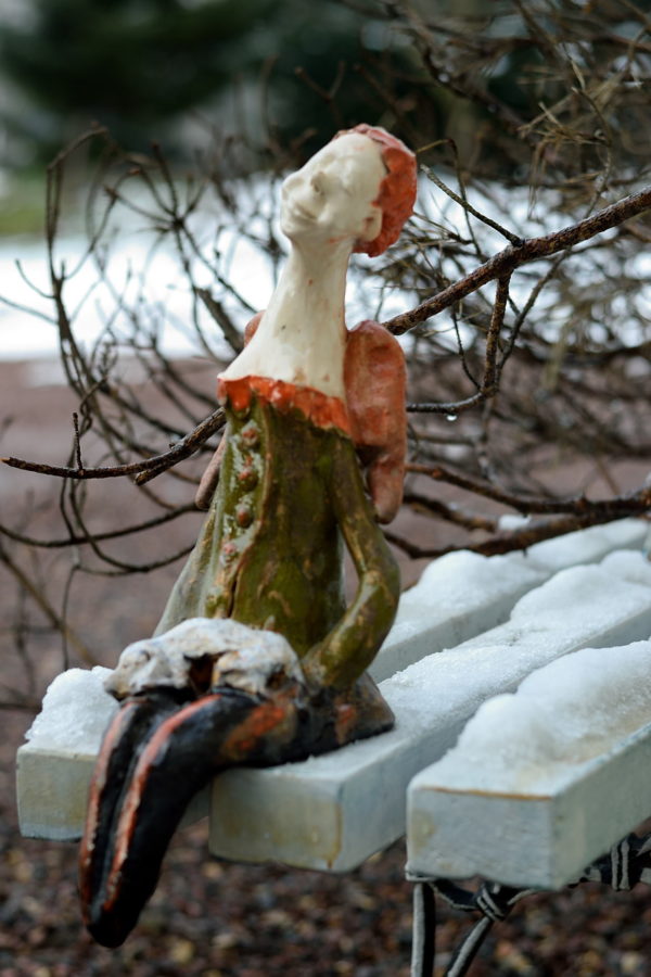 Ceramiczna rzeźba anioła trzymającego psa. Ceramiczny anioł w zielonym kolorze. Siedzący anioł na komodę