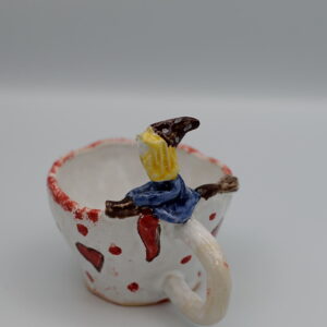 Mały, ceramiczny kubek z czarownicą.