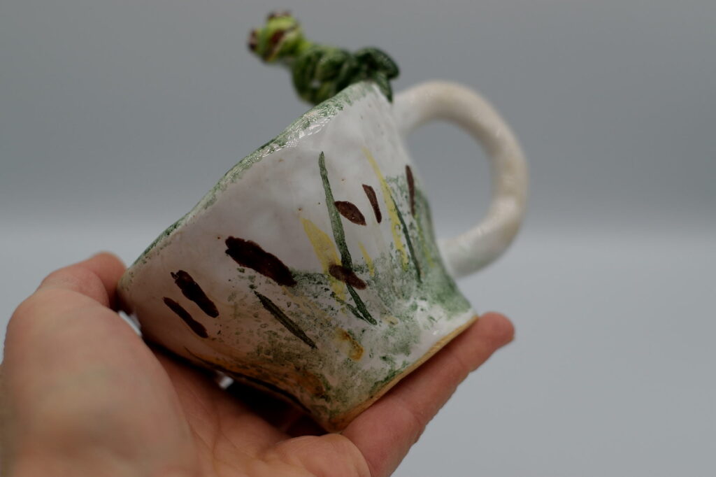 Mały, ceramiczny kubek z żabką.