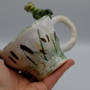 Mały, ceramiczny kubek z żabką.