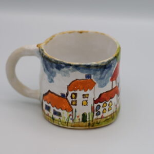 Ceramiczny kubek z malowanymi domkami.