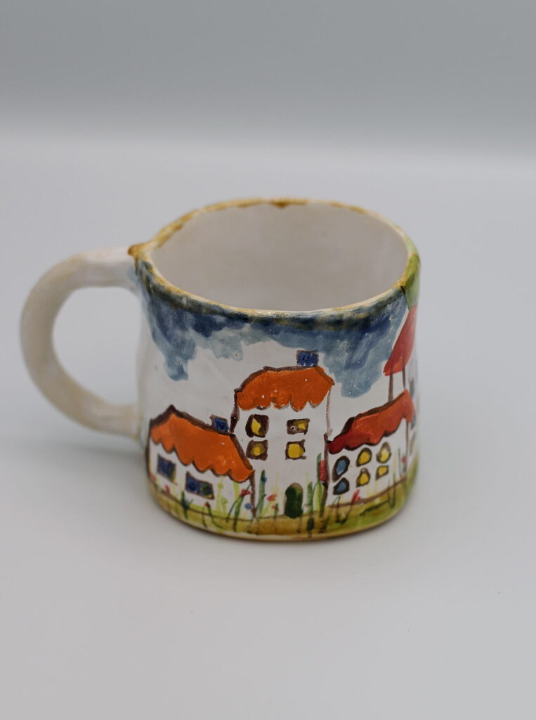 Ceramiczny kubek z malowanymi domkami.